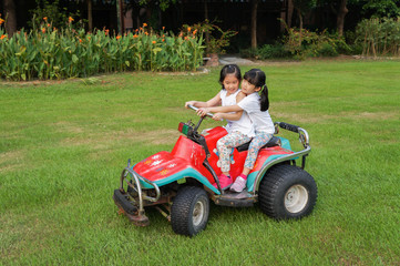 Asian girls enjoy driving ATV on the green grass field