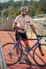 Pensive male cyclist standing on the bridge