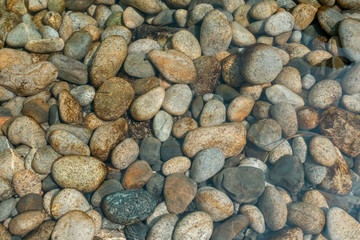 Background. Marine polished gray pebbles under water