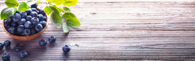 Blueberries in wood bowl on wooden table background.