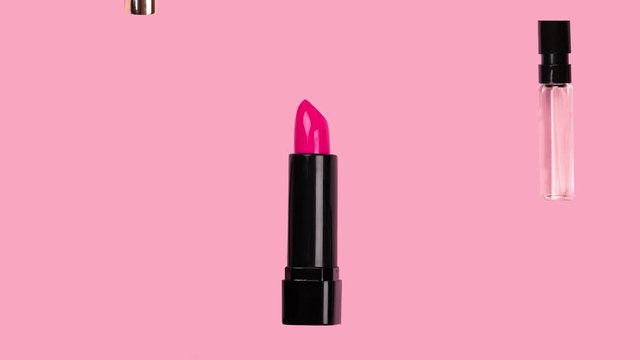 Different makeup accessories fly on trendy pastel pink background. Beauty animation. Cosmetic products. Make-up tools set concept. Lipstick, mascara, brush, perfume, nail Polish fall down. Skin care.