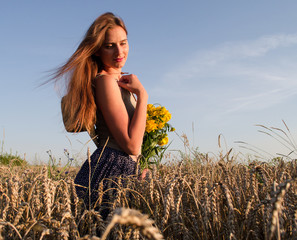 A beautiful woman walks in a field and holds a bouquet of wildflowers,
the girl in the hat smiles and looks into the distance,
a walk among the ears of wheat in August,
natural beauty without makeup