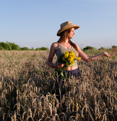 A beautiful woman walks in a field and holds a bouquet of wildflowers,
the girl in the hat smiles and looks into the distance,
a walk among the ears of wheat in August,
natural beauty without makeup