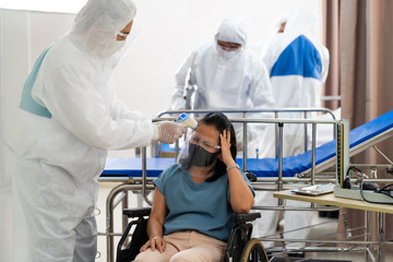 Doctor and medical technicians in protective disease PPE suit uniform and face mask Checking infected patient in quarantine room