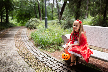 Little Girl in costume of red hat in the park. Happy Halloween concept