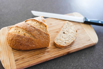 simple food ingredients, wholegrain rye bread on cutting board with bread knife next to it