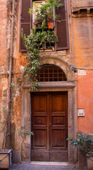 Fototapeta na wymiar An aging apartment doorway with an arch above and potted plants above that offer quaint character typical of Rome, Italy and Italian living.