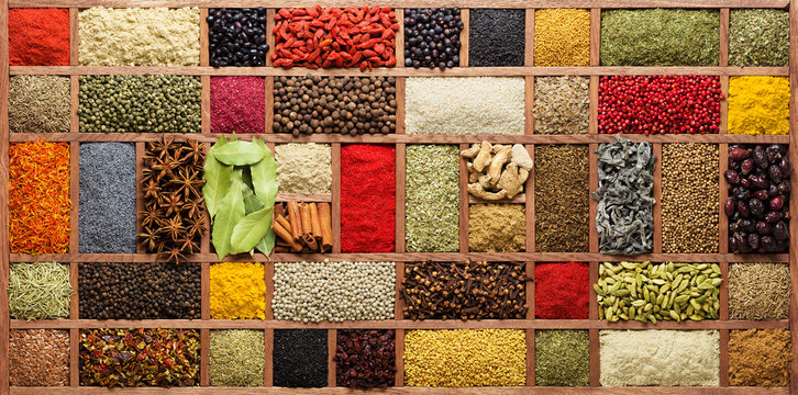Spices and herbs in wooden box, top view. Seasonings from all over the world for cooking food. - Powered by Adobe