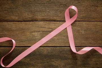 Pink ribbon on wooden breast cancer awareness background concept