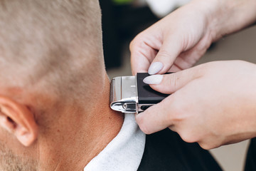 A handsome blond man of European appearance is doing a haircut. Close-up photo. Man at the barber shop