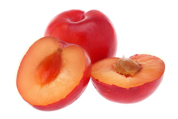 Isolated plums. One and a half of red plum fruit with leaves isolated on white background.