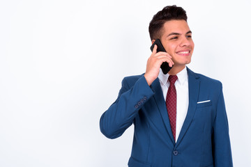 Portrait of happy young handsome multi ethnic businessman in suit talking on the phone