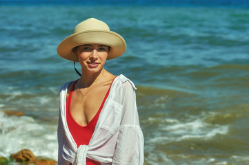 Portrait of a young woman on the sea coast . Beautiful woman in a straw hat by the sea .