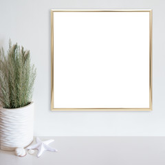 Gold frame mockup on white wall with beach/ocean theme decoration on white surface. Copy space.