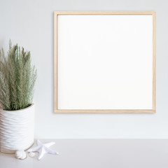 Wood frame mockup on white wall with beach/ocean theme decoration on white surface. Light wood. Copy space.