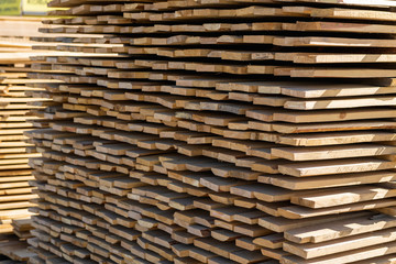 Wooden beam, stacked at construction site. Wooden planks, lining, boards for construction works in the sawmill. Timber mill.