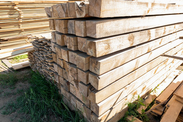 Raw wood beam, stacked at construction site. Wood texture, background. Wooden planks, lining, boards for construction works in the sawmill. Timber mill.