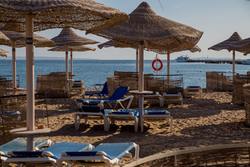 sandy beach with sun loungers thatched umbrellas