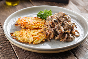 Potato pancakes with beef stroganoff on grey plate