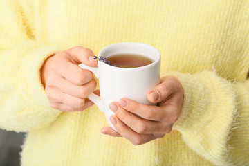 Woman with cup of hot tea at home, closeup