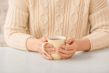 Woman with cup of hot tea at table