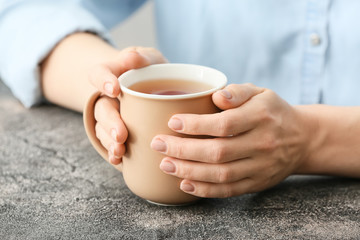 Woman with cup of hot tea at table, closeup