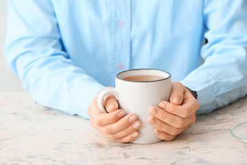 Woman with cup of hot tea at table