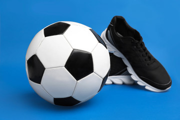 Soccer ball and shoes on color background