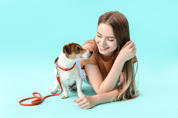 Young woman with cute dog on color background