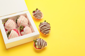Box with tasty glazed strawberry on color background