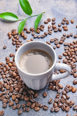 Cup of hot coffee and beans on table
