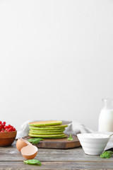 Tasty green pancakes with ingredients on table