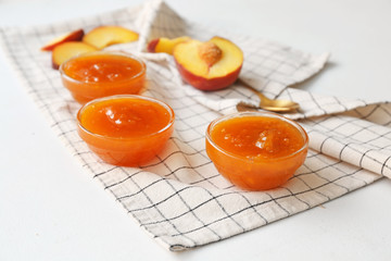 Bowls of tasty peach jam on white background