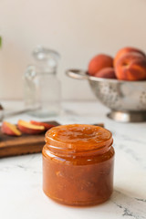 Jar of tasty peach jam on table