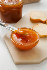 Bowl of tasty peach jam on table