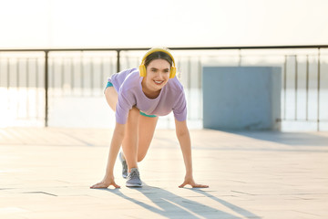 Sporty young woman with headphones training outdoors