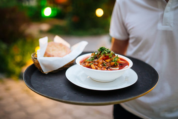 Waiter holding tray with uyghur dish guiru lagman