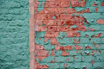Full frame of a brick wall painted with bright turquoise paint, cracked in several places.