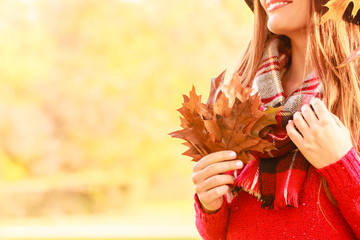 Female with maple leaves in hand. Autumnal park scenery