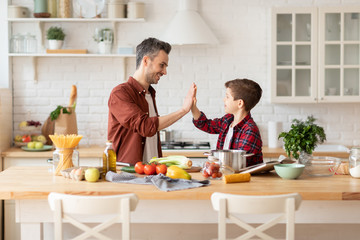 Happy father give five to loving son on kitchen