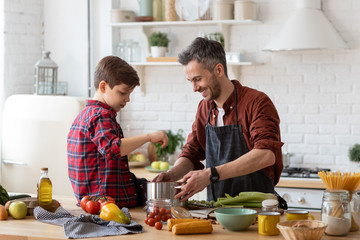 Happy father son prepare water for cooking pasta