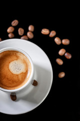 White cup of coffee with sprinkled beans. Black background. Vertical.