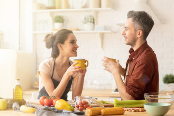 Happy couple drinking tea or coffee on kitchen