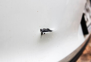 Scratch on the rear bumper of a white car.