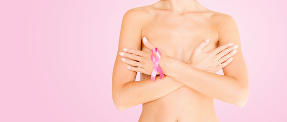 health, medicine and people concept - young woman checking breast with cancer awareness ribbon over...