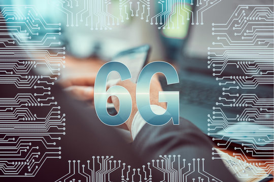 Circuit board on the background of a man working on a laptop and holding a smartphone in his hands. Caption: 6G