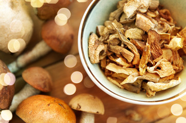 culinary, food and cooking concept - dried mushrooms in bowl on wooden background