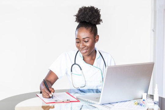 African American Doctor working in hospital writing a prescription, Healthcare and medical concept,test results in background, Stethoscope with clipboard and Laptop on desk