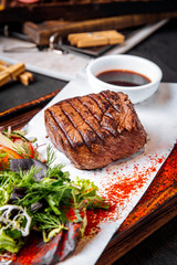 Fillet mignon steak on board with salad and sauce