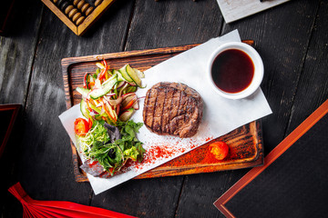 Fillet mignon steak on board with salad and sauce